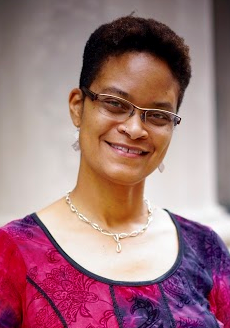 Image of a smiling Black woman with short hair and glasses facing the camera.