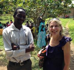 Smiling Drs. Diane Havlir and Moses Kamya standing outside with a group of people behind them